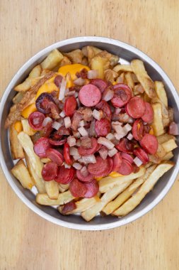 Kızartma. Dilimlenmiş sosis ve kıtır pastırmalı kızarmış patatesler ahşap arka planda metal bir kapta..