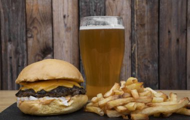 Geleneksel çizburger, çedar, soğan, patates kızartması ve bir bardak bira..