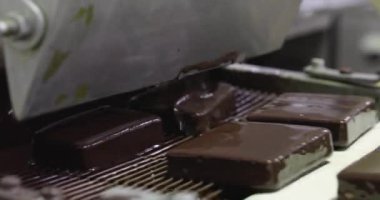 Yiyecek endüstrisi. Otomasyon ve teknoloji. Bombon suizo adı verilen endüstriyel dondurmayı çikolatayla kaplayan makinenin yakın görüntüsü..