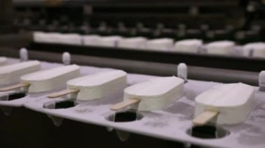 Yiyecek endüstrisi. Otomasyon ve teknoloji. Endüstriyel dondurma üretim süreci. Donmuş taşıma bandı boyunca dondurma taşıyan dondurma fabrikası makinesinin görüntüsü.