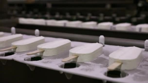 食品産業について オートメーションと技術 産業用アイスクリーム製造工程 冷凍コンベヤーバンドに沿ってクリームを輸送するクリームポップスル工場機械のビュー — ストック動画