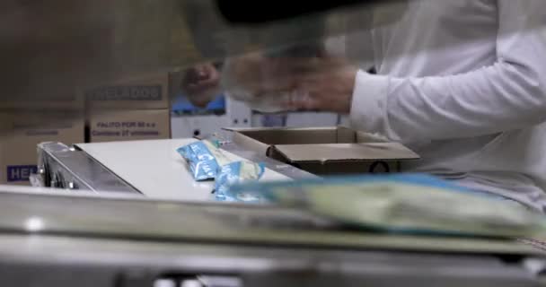 食品産業と技術について プラスチックパッケージにアイスクリームポップスを包む商業包装機のクローズアップビュー 背景の製品をボクシングする工場労働者 — ストック動画