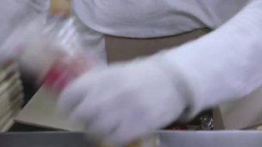 Gıda üretim süreci. Eldiven giyen bir adamın yakından görüntüsü, ticari buzlu şekerleri kutuya koyup teslim edilmeye hazır hale getiriyor.