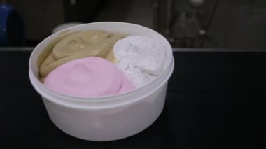 Dondurma fabrikası. Ticari dondurma tencerelerini farklı tatlarda taşıyan bir taşıma bandının yakın görüntüsü.