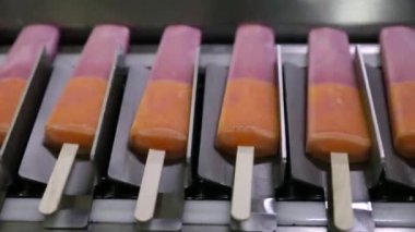Yiyecek endüstrisi. Gıda üretiminde otomasyon ve teknoloji. Ticari çilek ve portakal aromalı buzlu şeker makinesinin en üst görüntüsü ürünü taşıyor..