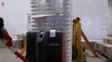 Gıda endüstrisi ve imalat. Beyaz plastik kaplarda gıda ürünleri taşıyan bir işçiyi depolamak için asansöre taşırken görmek.