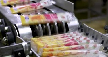 Yiyecek endüstrisi. Ticari çilek ve portakal aromalı buzlu dondurma taşıma bandı ürünü teslimat için buz kutularını kutulayan bir fabrika işçisine taşıyor..