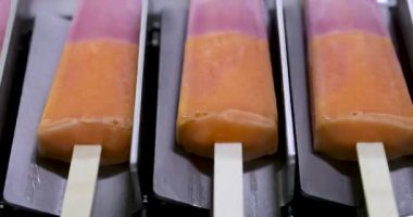 Yiyecek endüstrisi. Gıda üretiminde otomasyon ve teknoloji. Ticari çilek ve portakal aromalı buzlu şeker makinesinin en üst görüntüsü ürünü taşıyor..