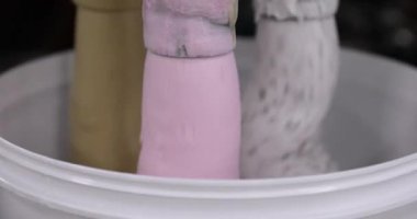 Yiyecek endüstrisi. Teknoloji ve otomasyon. Ticari plastik dondurma tencerelerini farklı tatlarla dolduran bir makinenin yakın görüntüsü.