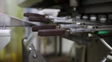 Sanayi dondurma fabrikası. Gıda üretim sektöründe otomasyon ve teknoloji. Çikolatayla kaplanmış dondurma taşıyan ve ambalajlayan bir makine görüntüsü.