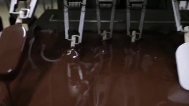 Sanayi dondurma fabrikası. Gıda üretim sektöründe otomasyon ve teknoloji. Çikolataya kremalı dondurma taşıyıp batıran bir makine görüntüsü.