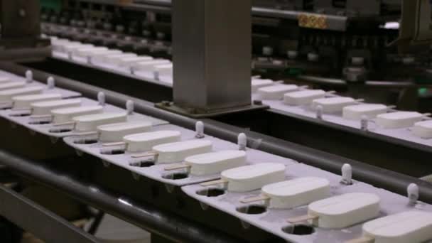 食品産業について オートメーションと技術 産業用アイスクリーム製造工程 冷凍コンベヤーバンドに沿ってクリームを輸送するクリームポップスル工場機械のビュー — ストック動画