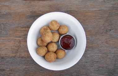 Peynir topları. Patates ve mozzarella peynirli kroket, ahşap masada beyaz bir kasede acı biber soslu..
