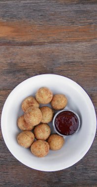 Peynir topları. Patates ve mozzarella peynirli kroket, ahşap masada beyaz bir kasede acı biber soslu..