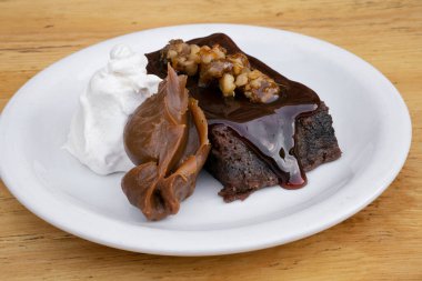 Tatlı tatlılar. Yakından bakınca, vanilya kremalı acı-tatlı çikolatalı turta ve ahşap masada beyaz bir tabakta 