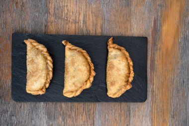 Geleneksel et kızartması. Tahta masadaki siyah tabakta üç doldurulmuş turtanın en üst görüntüsü..