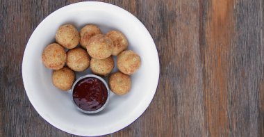 Peynir topları. Patates ve mozzarella peynirli kroket, ahşap masada beyaz bir kasede acı biber soslu..