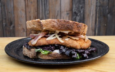 Ekmek, parmesan peyniri, marul, domuz pastırması ve kızarmış tavuk bifteği ile yapılmış lezzetli bir sandviç..