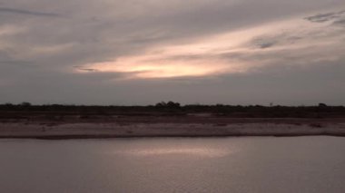 Dramatik bir günbatımı gökyüzünün altındaki nehrin panorama manzarası. Güzel güneş ışığı ve bulutlar su yüzeyinde yansıyor..