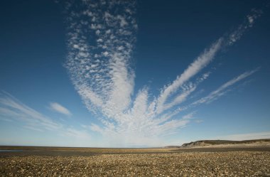 Deniz kıyısı kayalık sahili ve dramatik bulutlarla dolu derin mavi gökyüzü..