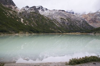 Dağın tepesinde büyülü bir buzul gölü var. And Dağları 'nın manzarası, kayalık kıyı, orman ve Ushuaia, Arjantin' deki turkuaz rengi Emerald Gölü 'ndeki yansıması..