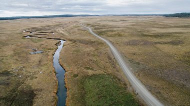 Kırsal alan. Sonbaharda sarı çayırlarda akan toprak yol ve derenin havadan görünüşü..