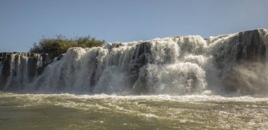 Navigating the rapids. The majestic Mocona falls seen from the boat. The rocky waterfall white water, strong river current flowing across the jungle. clipart