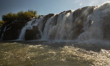 Gün batımında Mocona şelalesinde. Mocon 'un güzel manzarası, alacakaranlıkta, nehirde seyreden bir gemiden, güzel bir mercek parıltısıyla birlikte düşer..