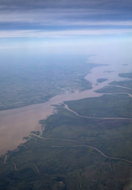 Uçuyorum. Amazon nehrinin havadan görünüşü, akarsular ve akarsu kanalları yeşil yağmur ormanı ve tarlaları boyunca akar, güzel mavi bir gökyüzünün altında.. 