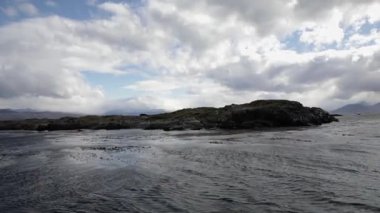 Patagonya 'ya yelken açmak. Kanal Okyanusu ve kayalık adaları dramatik bir günbatımı gökyüzü altında güzel bulutlarla