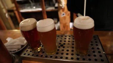 Bardakları dolduruyorum. Tezgahtaki bira musluklarının altında 3 litre soğuk ve köpüklü bira servisi yapan bir barmenin yakın çekimi.. 