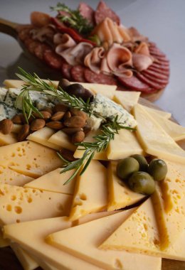 Parmak yiyeceği. Peynir tahtası, gruyere, rokfor peyniri, feta ve salam, jambon ve prosciutto ile yakın plan görüntüsü.