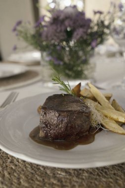 Gurme gastronomi. Düğün ana yemeği. Yakından bakınca, kırmızı şarap soslu ızgara fileto ve masada güzel kurulmuş patatesler görünüyor.