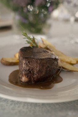 Gurme gastronomi. Düğün ana yemeği. Yakından bakınca, kırmızı şarap soslu ızgara fileto ve masada güzel kurulmuş patatesler görünüyor.