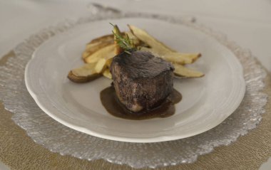 Gurme gastronomi. Düğün ana yemeği. Yakından bakınca, kırmızı şarap soslu ızgara fileto ve masada güzel kurulmuş patatesler görünüyor.