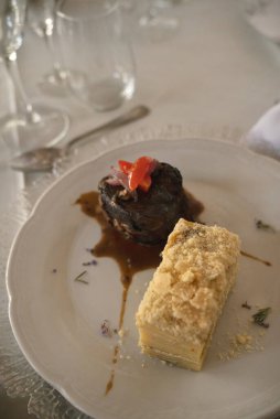 Sosyal bir etkinlikte gurme gastronomisi. Yakından bakınca soslu ızgara fileto ve galada beyaz bir tabakta patates mili feuille. 