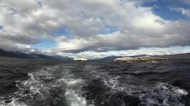 Beagle Kanalı 'nda okyanusa yelken açmak kayalık adadan uzakta Les Eclaireurs deniz fenerinin bulunduğu yerde bulutlarla kaplı güzel bir gökyüzünün altında duruyor.