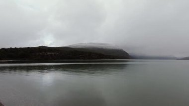 Patagonya 'da yağmur yağıyor. Gölün kenarında, kayalık kıyılarda, dağlarda ve fırtınalı bir gökyüzünün altında orman. Su yüzeyine düşen yağmur damlalarının görüntüsü