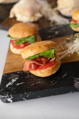 Gurme yemek servisi. Kanepeler. Domatesli ve roka aromalı jambonlu sandviçlerin yakın plan görüntüsü.