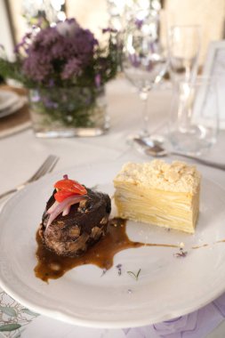Sosyal bir etkinlikte gurme gastronomisi. Yakından bakınca soslu ızgara fileto ve galada beyaz bir tabakta patates mili feuille.
