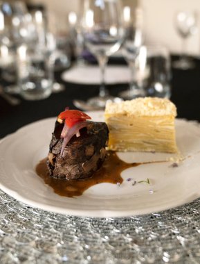 Sosyal bir etkinlikte gurme gastronomisi. Yakından bakınca soslu ızgara fileto ve galada beyaz bir tabakta patates mili feuille.