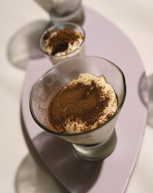 Yemek servisi güzelmiş. Açık mor tahta bir tahtanın içinde çikolata tozlu tiramisu bardaklarının yakın görüntüsü 