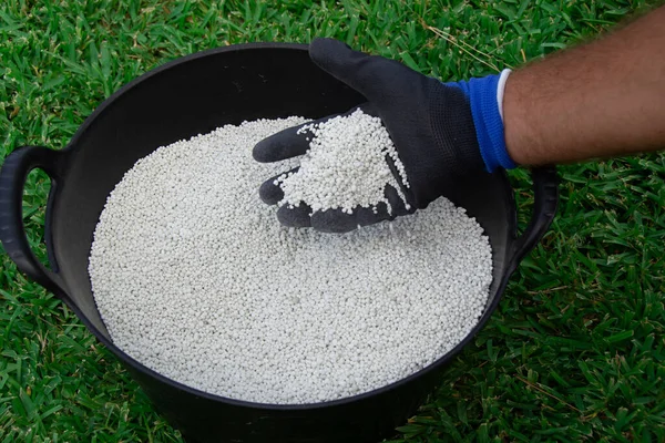 stock image Bucket of white chemical fertilizer in granular format ready to be applied to garden plants. Garden maintenance concept.