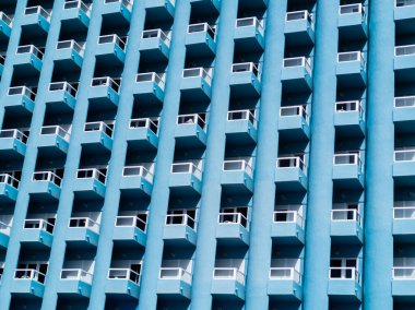 Ön cephesi maviye boyanmış bir otelin balkonları. Mimaride Geometri.