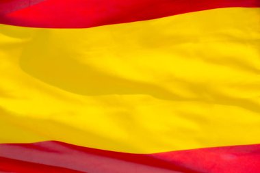 İspanyol bayrağına yakın çekim, arması olmadan, rüzgarda sallanarak. İspanyol bayrağı tüm çerçeveyi işgal ediyor.