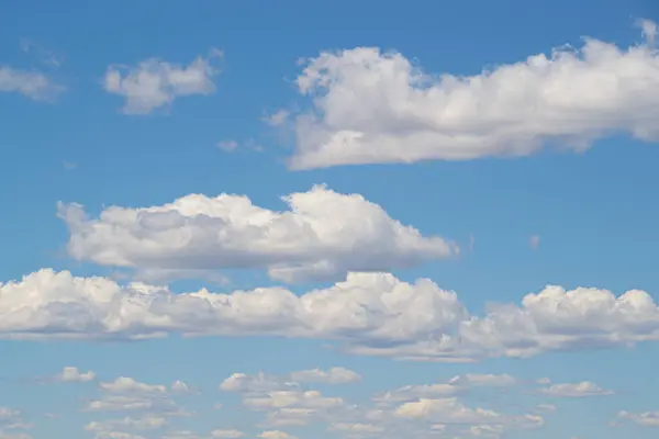 stock image Textured clouds spread horizontally across a vast blue sky on a bright day.