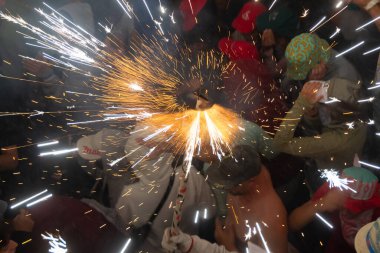Correfoc, 24 Haziran 2024 'te İspanya' nın Javea kentindeki San Juan şenliklerinde. Genç kapüşonlu adamlar tarafından kucaklanan korrefok şeytanının yakın çekimi..