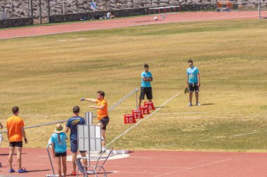 Spor giyimli atletik bir adam ve arka planda bir stadyumda iple dolaşan bir tişört..
