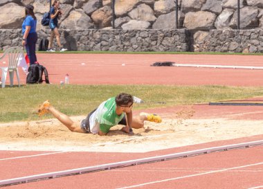 Sporcu kumda zıplıyor.