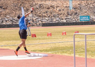 Spor giyimli genç bir erkek sporcu sahada koşuyor.